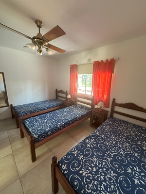 Habitación luminosa con tres camas individuales, ideal para familias